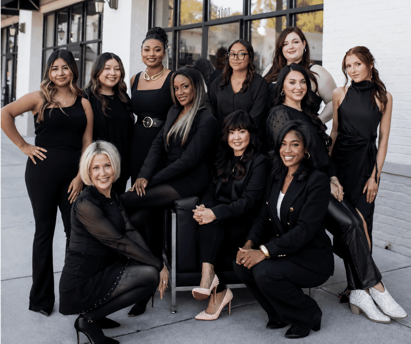 Group of eleven women, all dressed in black, posing outside a building.