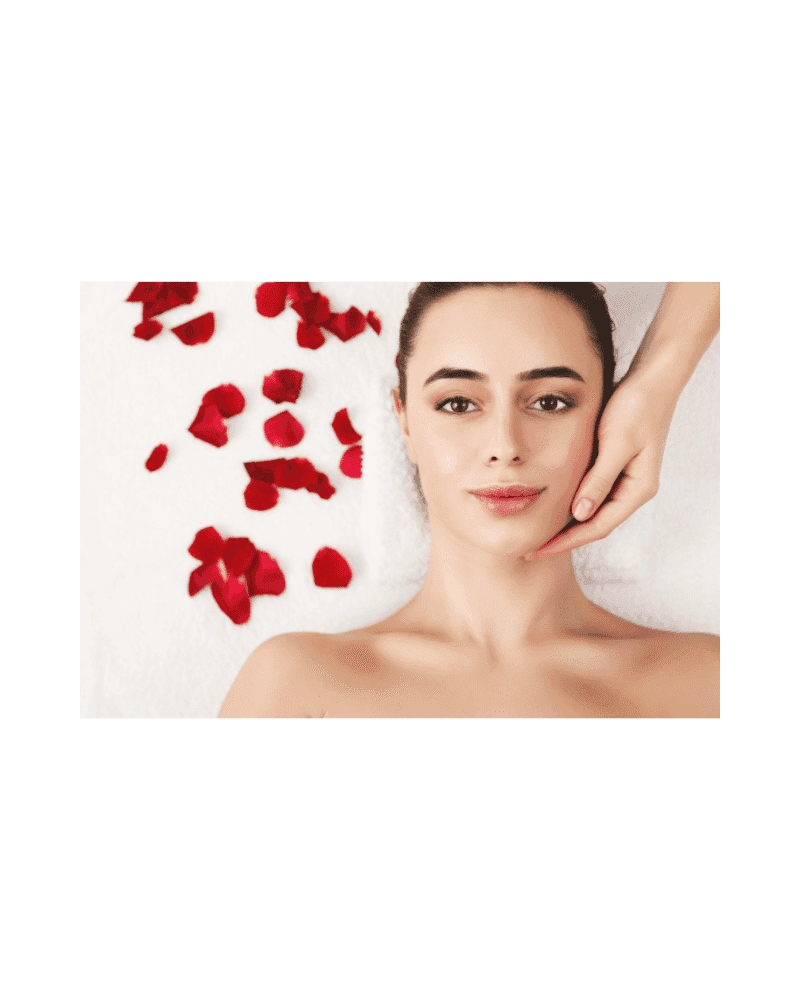 Woman receiving facial massage with rose petals on white towel background.